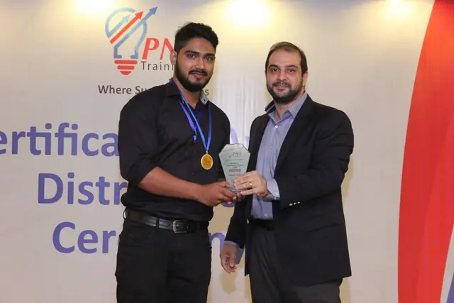 Usman Saeed receiving an award shield and medal at the PNY Trainings certificate distribution ceremony, Lahore
